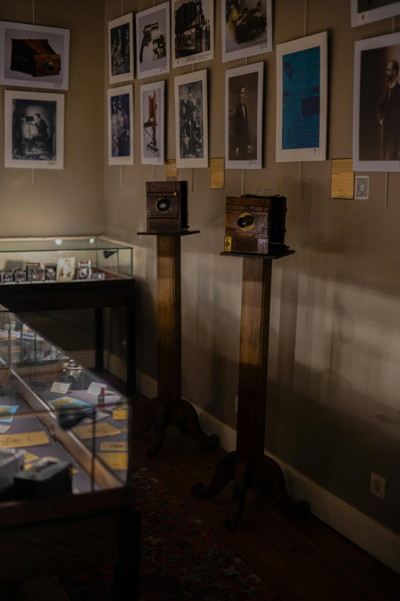 A collection of vintage cameras and historical photographs in a dimly lit museum room.